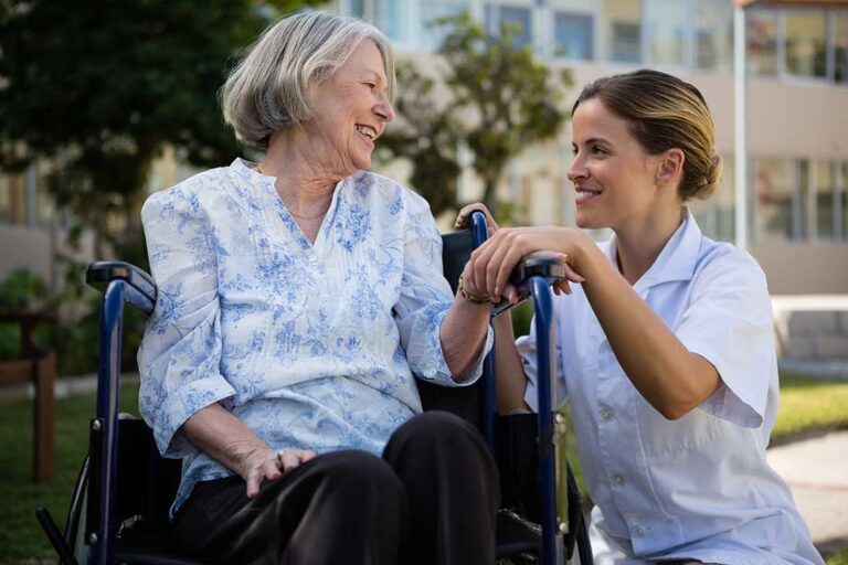 Older adults laughing and talking together while seated around a dining table in a comfortable communal room.